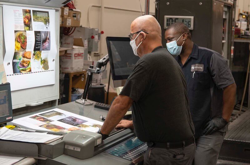 two print production specialists discussing a project